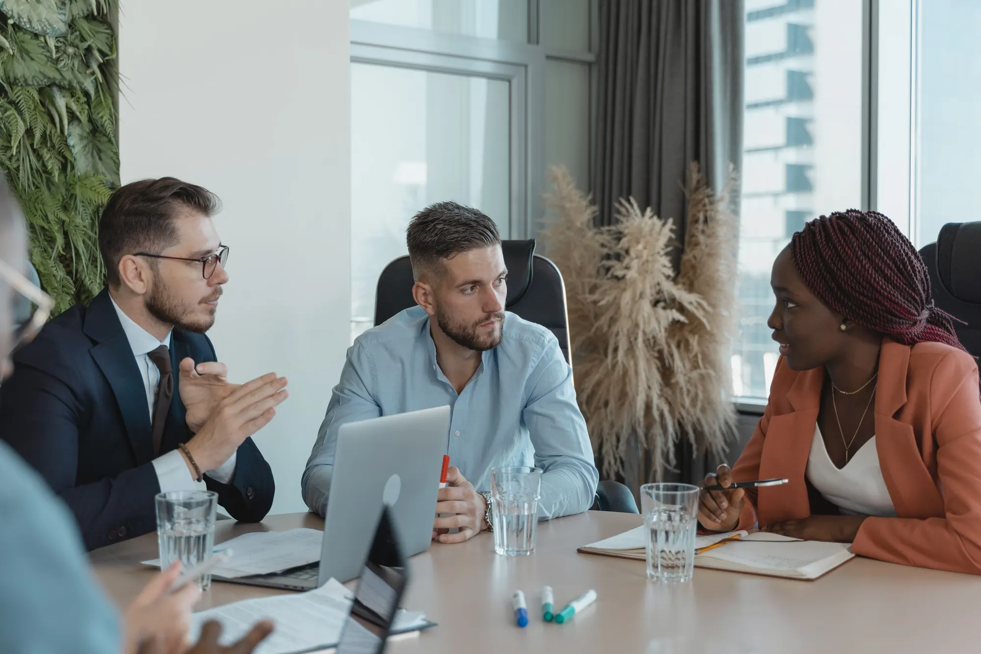 Equipe reunida em torno de uma mesa com laptops, discutindo um projeto